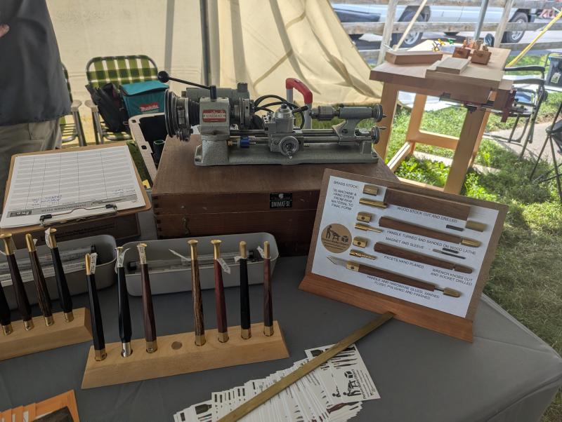 Tool maker booth with marking knives, a work in process steps board, and a tiny lathe.