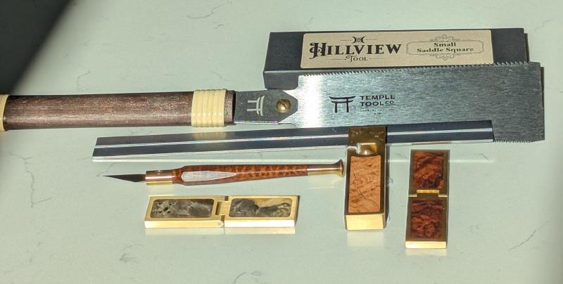A bunch of tools on a white countertop made of wood and brass gleaming in the sunlight.